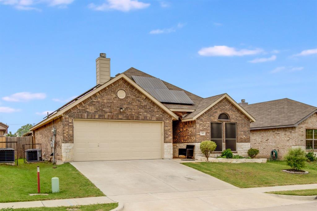 View of front of home featuring a chimney, brick siding, and a garage