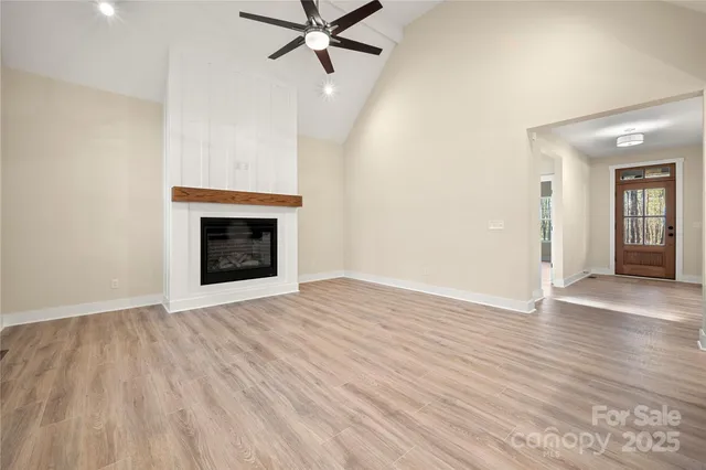 a view of an empty room with wooden floor and a fireplace