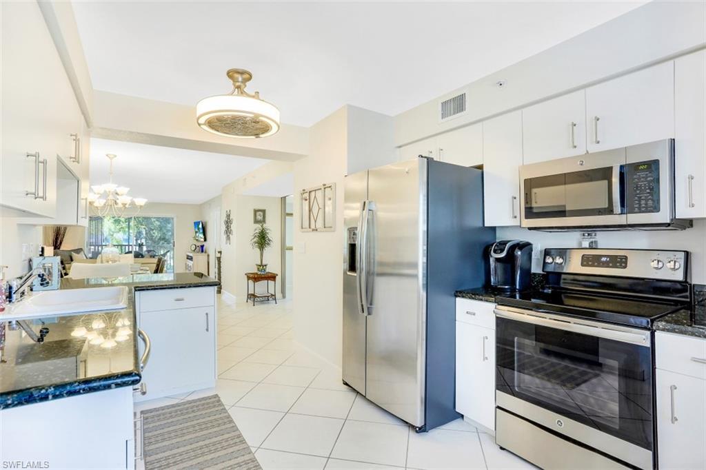 480 Bermuda Cove Way, Unit 1205 Naples, FL 34110 - Photo 11 of 33 a kitchen with stainless steel appliances granite countertop a refrigerator a stove and a sink