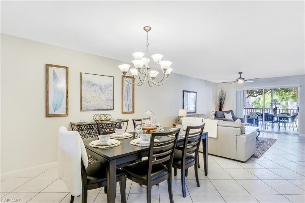 480 Bermuda Cove Way, Unit 1205 Naples, FL 34110 - Photo 17 of 33 a dining room with wooden floor a chandelier a wooden table and chairs