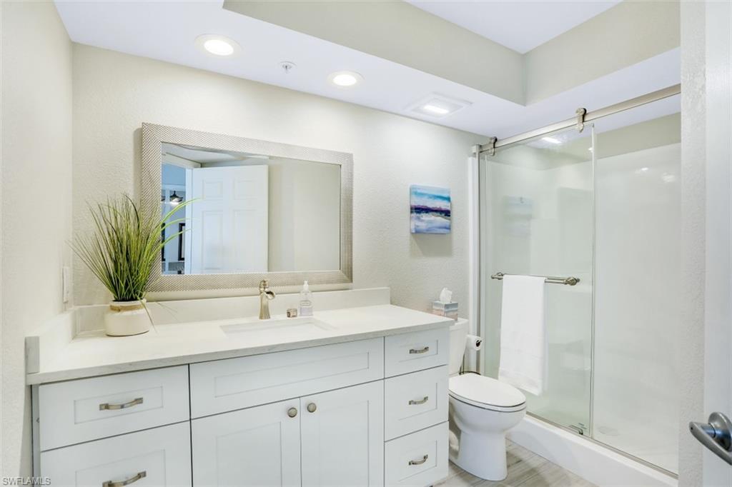 480 Bermuda Cove Way, Unit 1205 Naples, FL 34110 - Photo 20 of 33 a bathroom with a sink a toilet a large mirror and shower