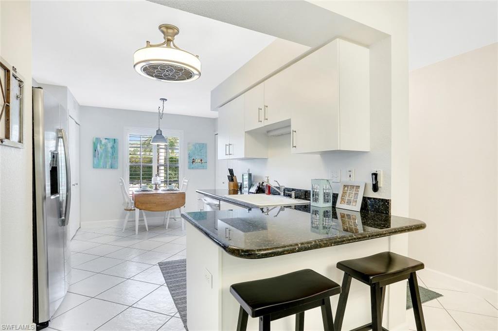 480 Bermuda Cove Way, Unit 1205 Naples, FL 34110 - Photo 10 of 33 a kitchen with a dining table and chairs