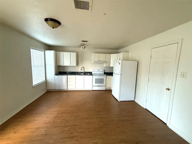 an empty room with wooden floor and white walls