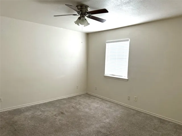 an empty room with a window and a fan