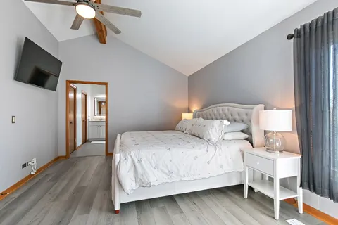 a bedroom with a bed wooden floor and flat screen tv