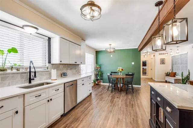 a kitchen with cabinets a sink dishwasher and a stove with wooden floor