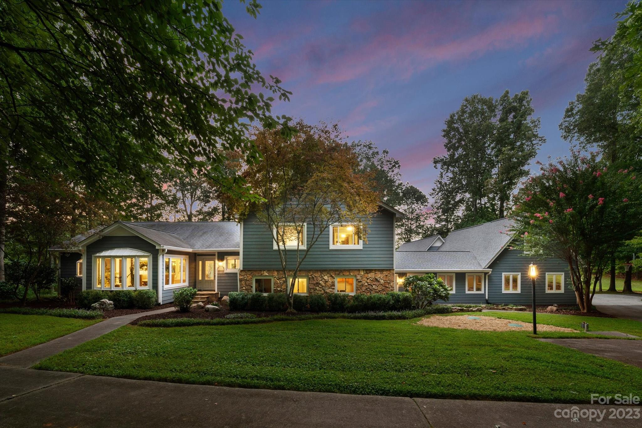 a front view of a house with garden and trees