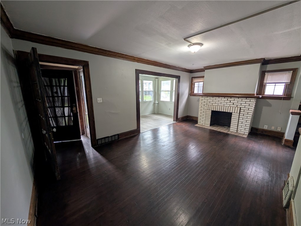 475 East 146th Street Cleveland, OH 44110 - Photo 4 of 28 Spacious living area featuring dark wood-finish flooring, a white brick fireplace, and prominent dark wood trim