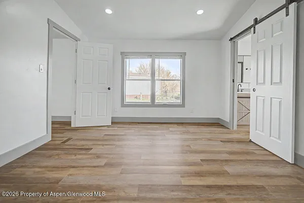 a view of an empty room with wooden floor and a window