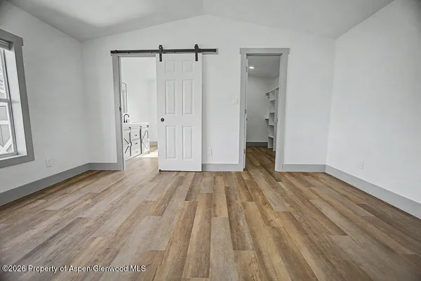 a view of a room with wooden floor and a bathroom