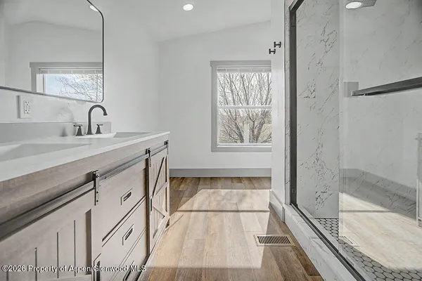 a spacious bathroom with a granite countertop sink a mirror and shower