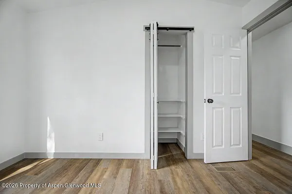 a view of empty room with wooden floor and closet