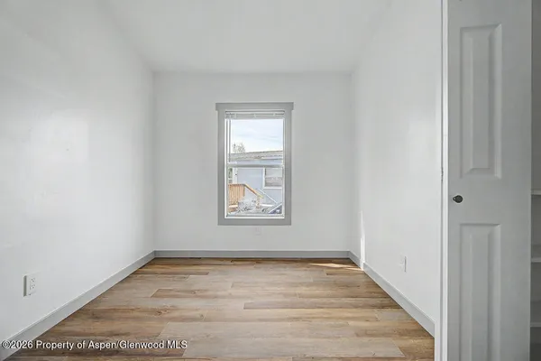 an empty room with wooden floor and windows