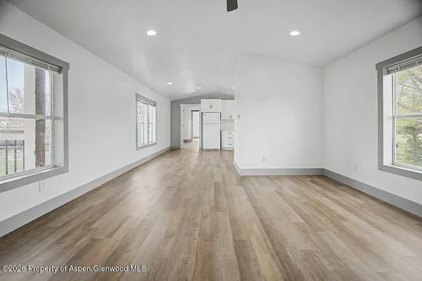 an empty room with wooden floor and windows