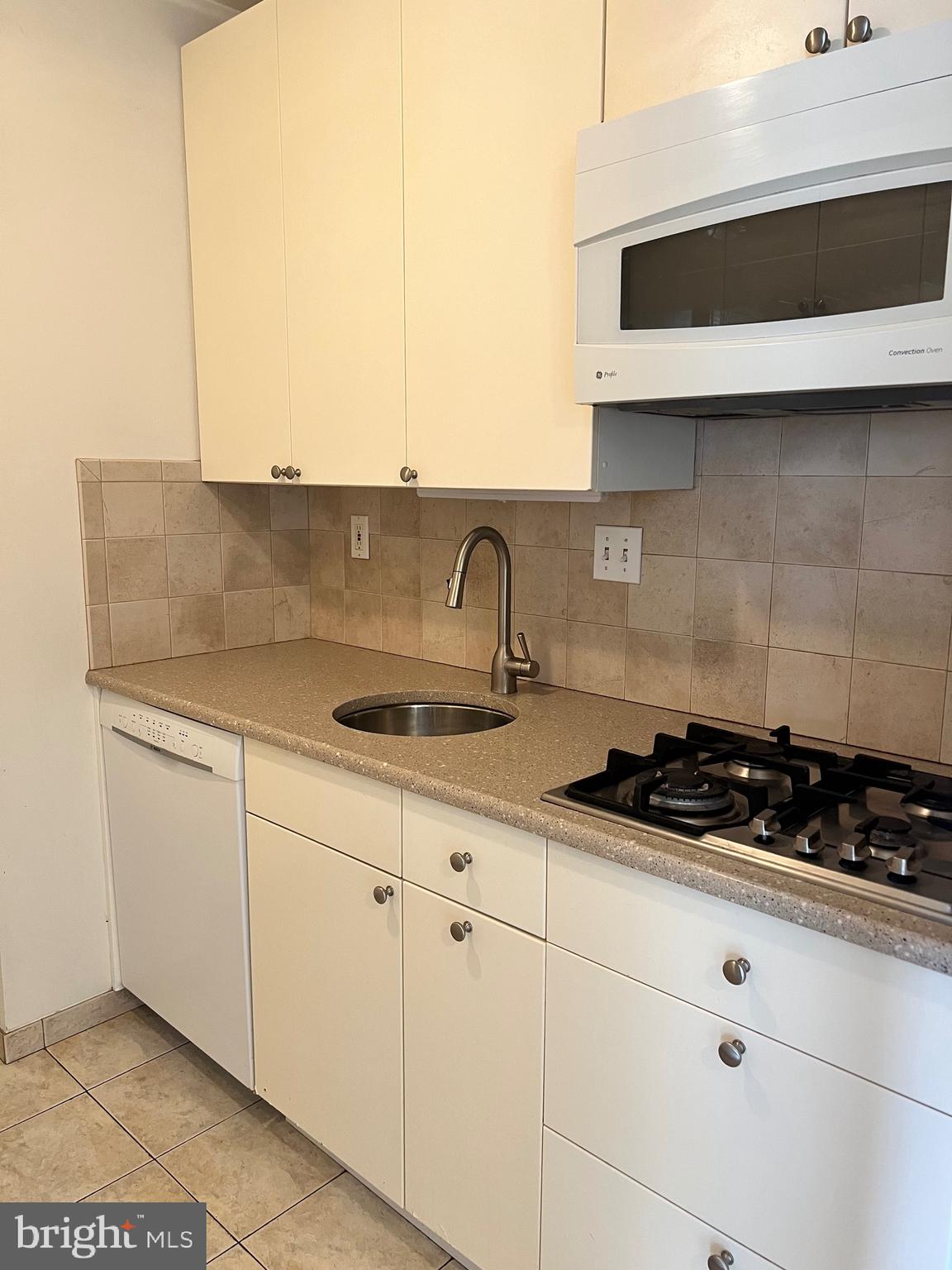 429 N Street Southwest, Unit S301 Washington, DC 20024 - Photo 6 of 19 a kitchen with granite countertop white cabinets and black appliances