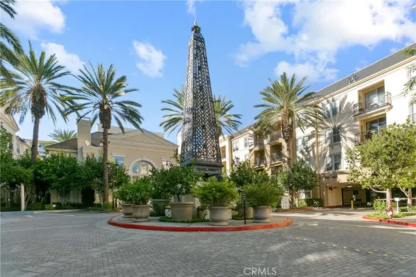 a palm tree sitting in front of a house with a large tree