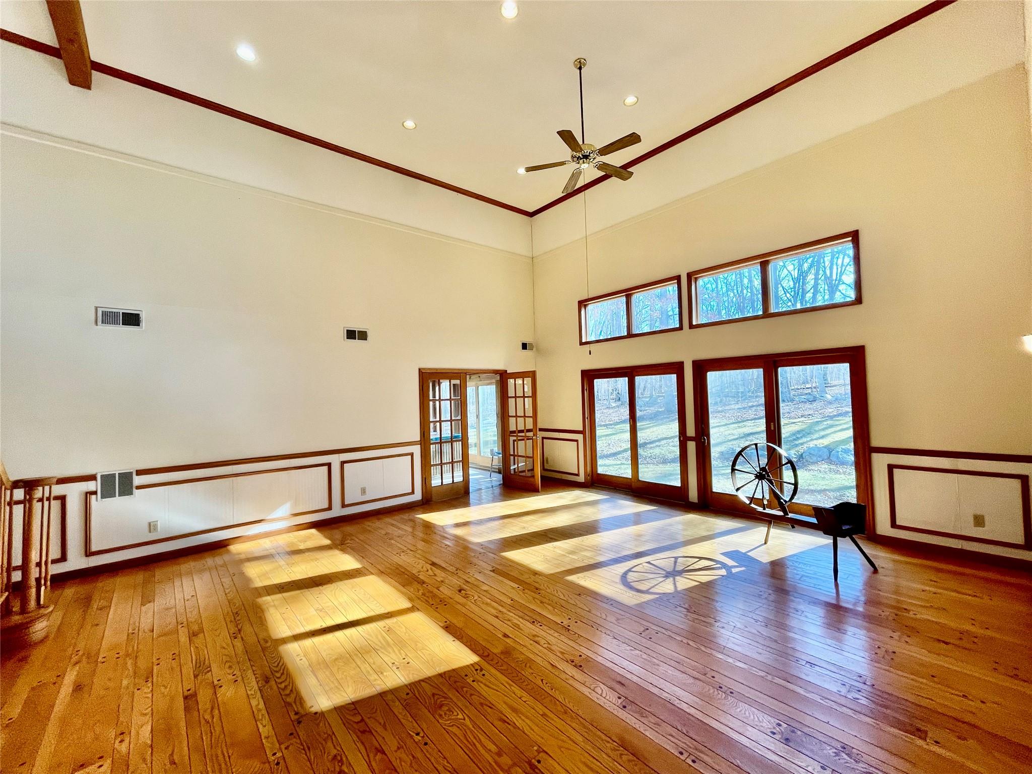 71 Saddleback Ridge Wallkill, NY 12589 - Photo 21 of 39 Unfurnished living room featuring wood-type flooring, french doors, a ceiling fan, a towering ceiling, and a decorative wall