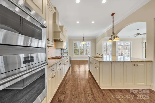 a large kitchen with stainless steel appliances granite countertop a lot of counter space and wooden floor