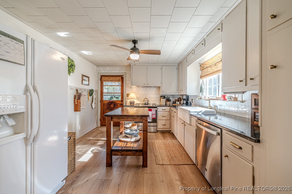 179 Sunset Hills Road Robbins, NC 27325 - Photo 12 of 31 a kitchen with stainless steel appliances a refrigerator a sink dishwasher a stove and white countertops with wooden floor