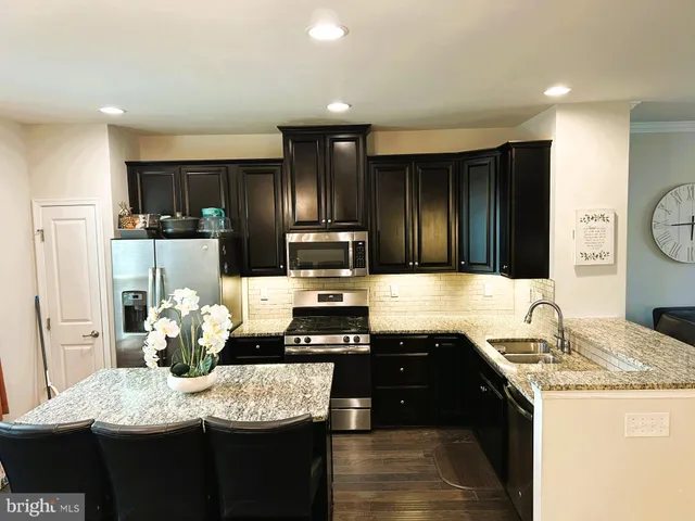 a kitchen with stainless steel appliances kitchen island granite countertop a refrigerator a stove top oven with a sink and dishwasher