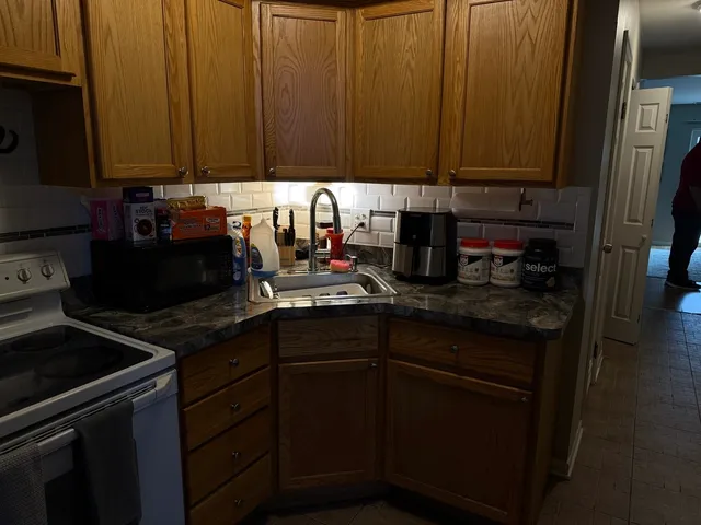 a kitchen with granite countertop a sink dishwasher stove and cabinets