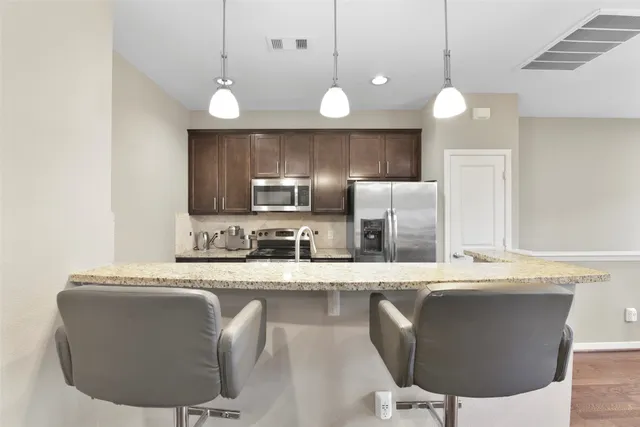 a kitchen with kitchen island granite countertop a sink cabinets and stainless steel appliances