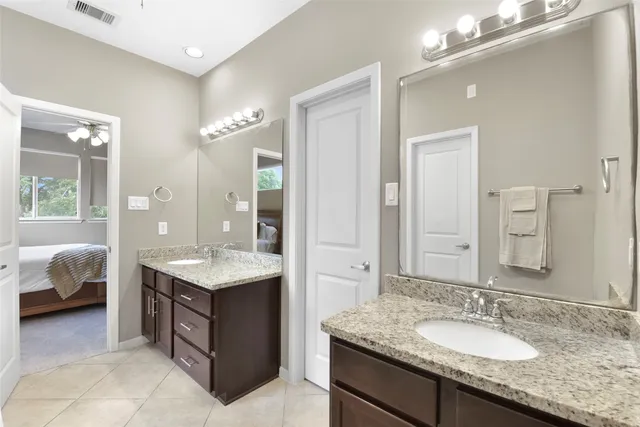 a en suite bathroom with a granite countertop double vanity sink a mirror and tub