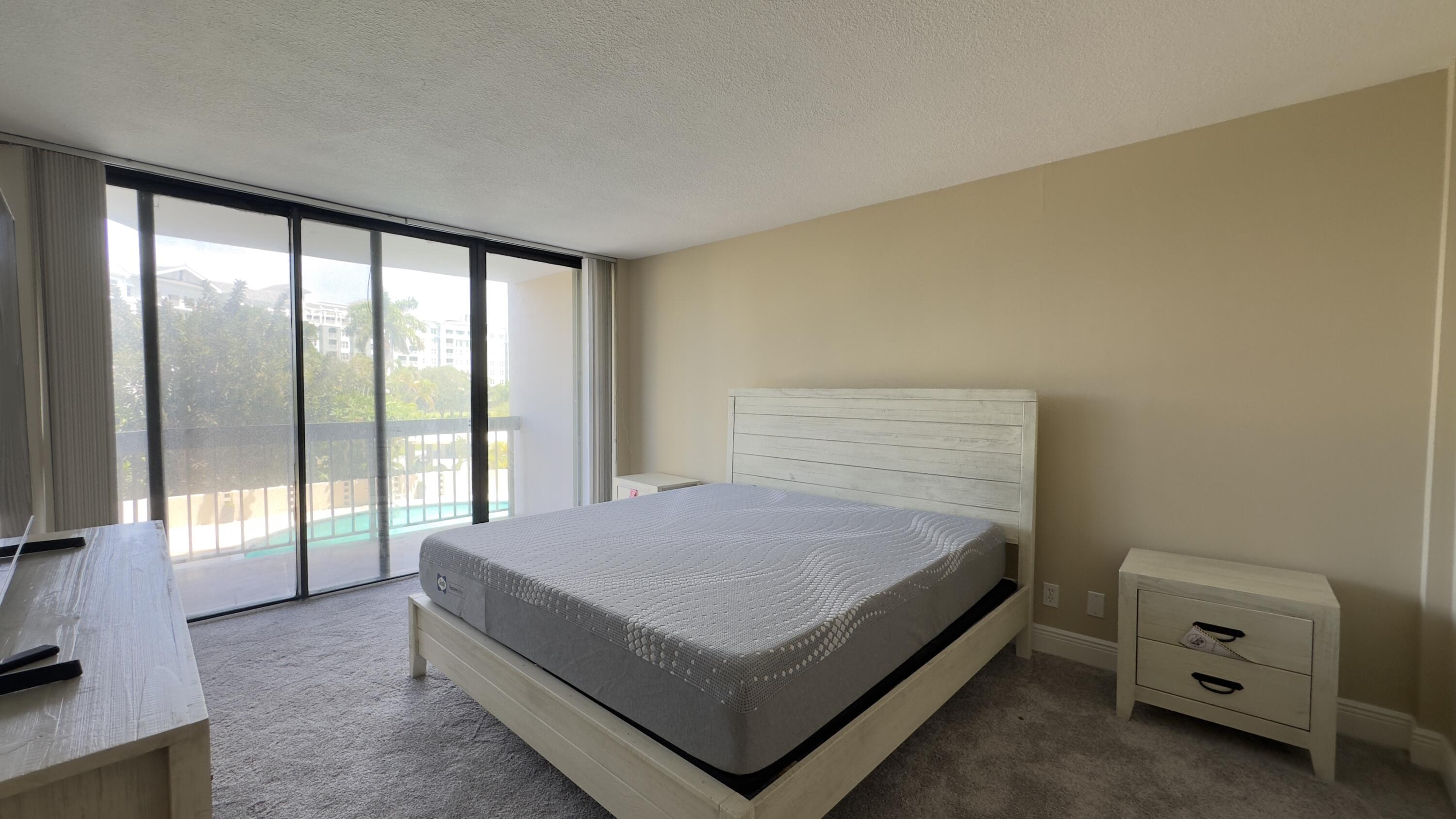 2425 Presidential Way, Unit 203 West Palm Beach, FL 33401 - Photo 11 of 35 a bed sitting in a room next to a window
