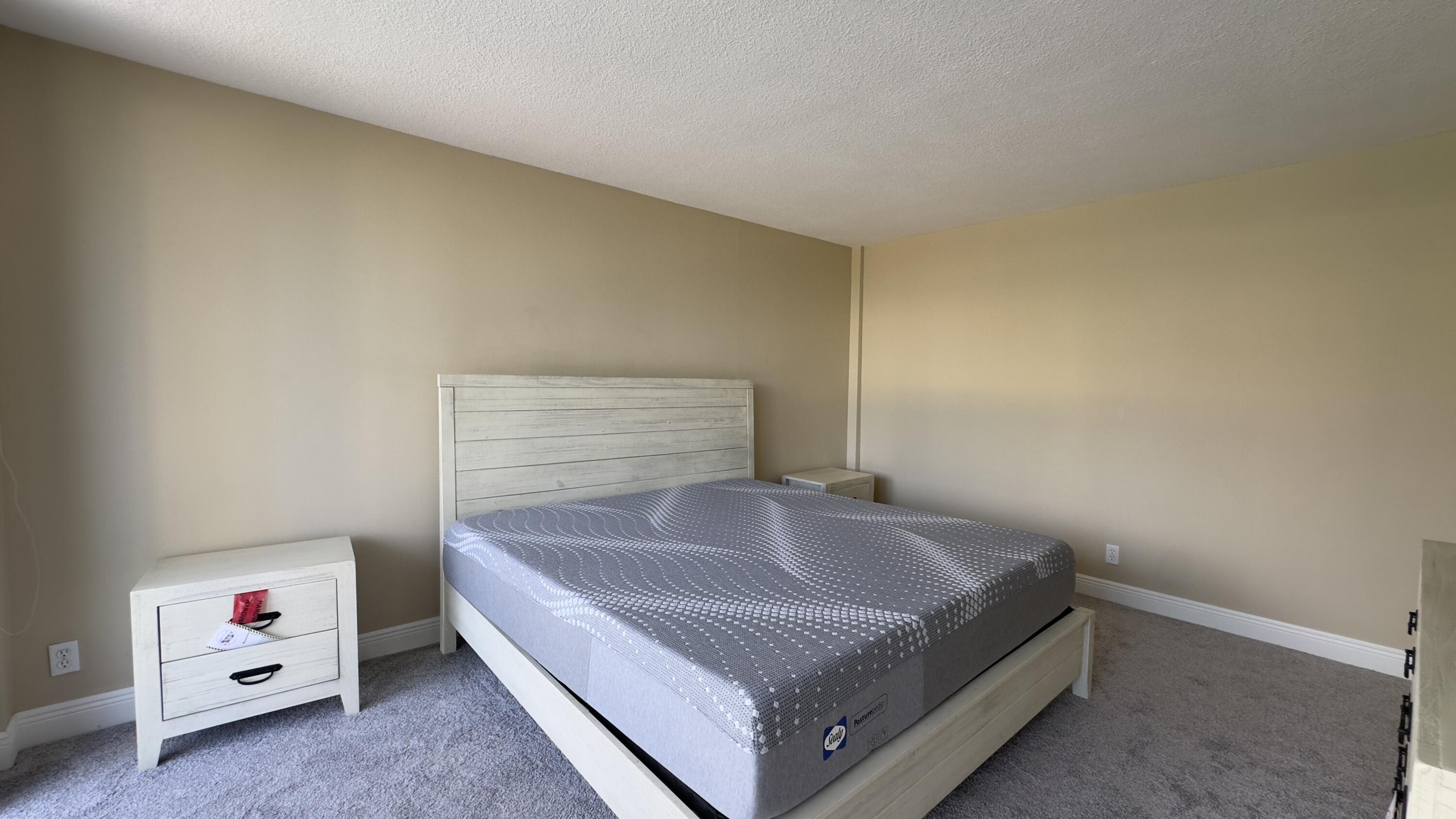 2425 Presidential Way, Unit 203 West Palm Beach, FL 33401 - Photo 12 of 35 a spacious bedroom with a bed and a window