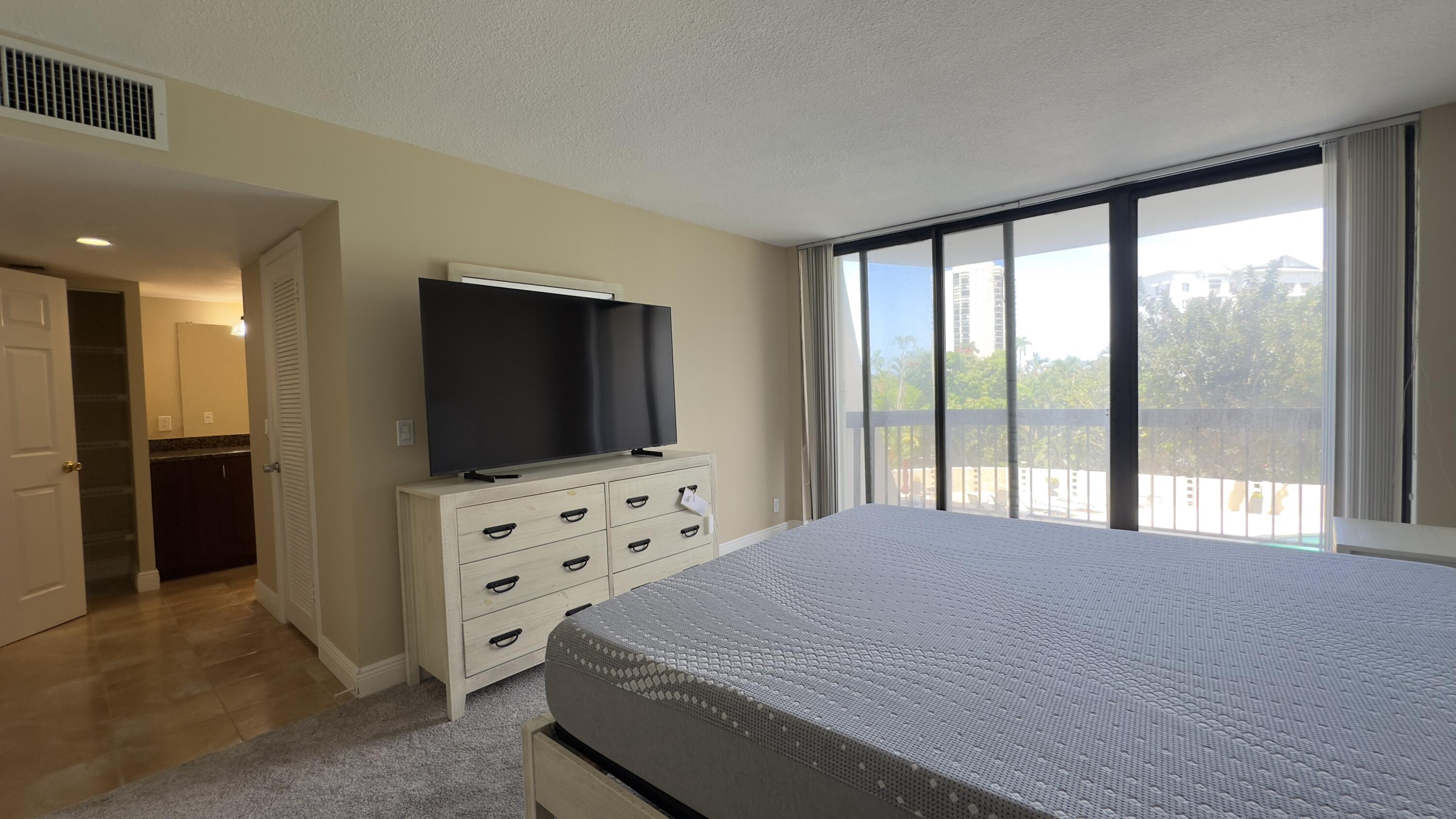 2425 Presidential Way, Unit 203 West Palm Beach, FL 33401 - Photo 13 of 35 a bedroom with a bed and a flat screen tv
