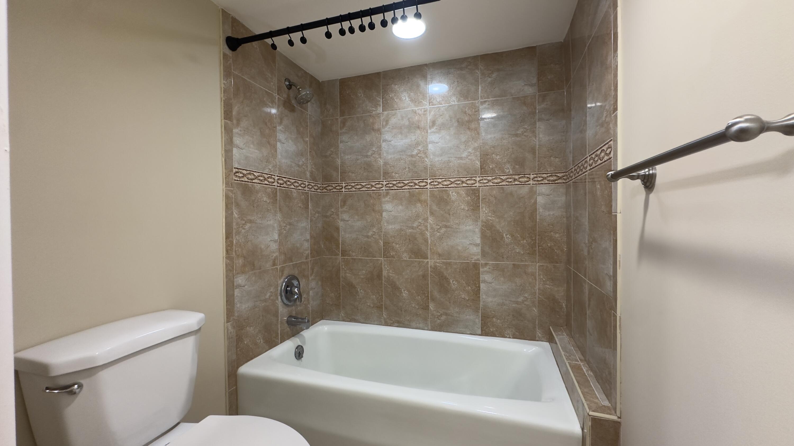 2425 Presidential Way, Unit 203 West Palm Beach, FL 33401 - Photo 16 of 35 a bathroom with a bathtub and a toilet