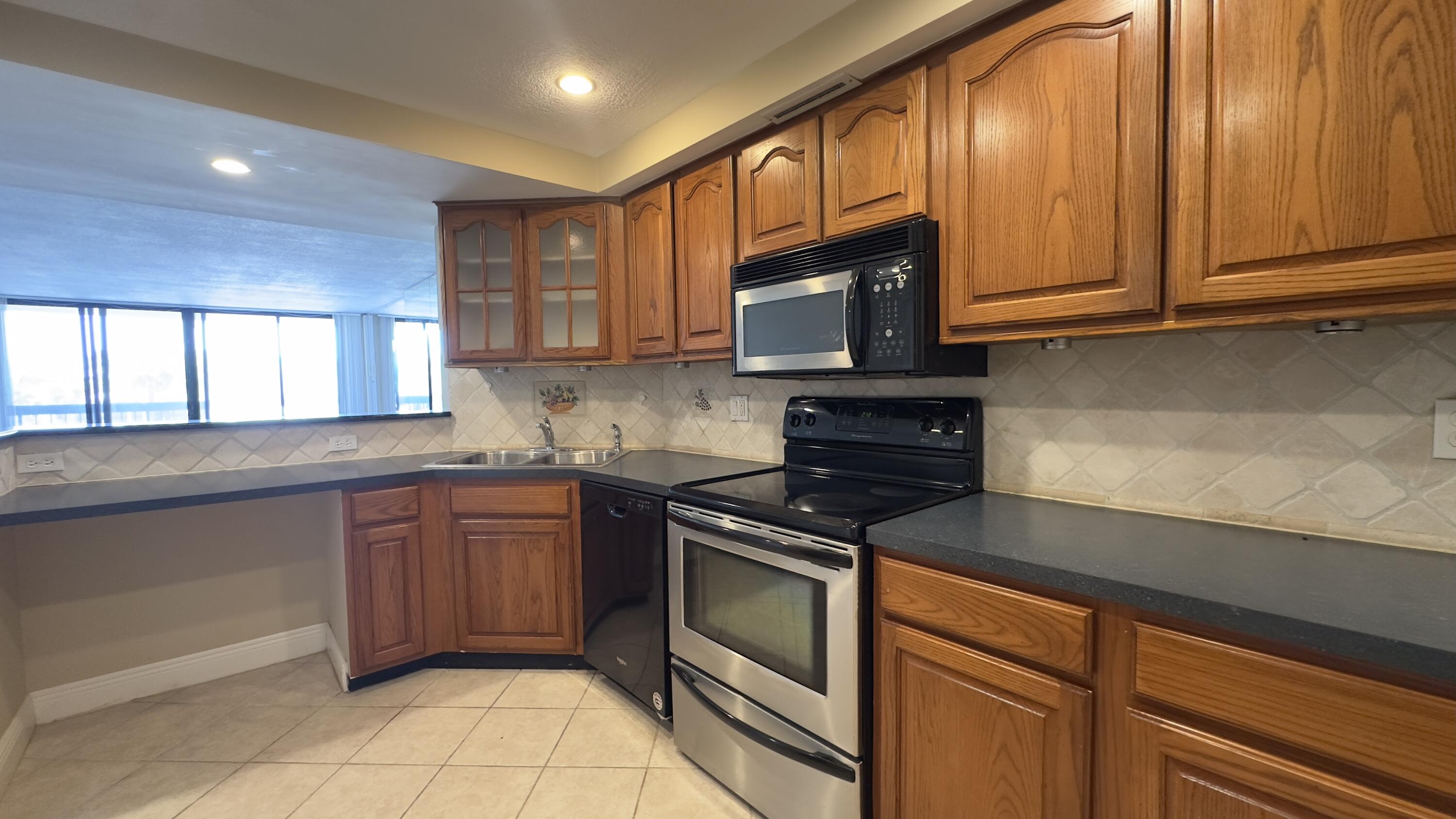2425 Presidential Way, Unit 203 West Palm Beach, FL 33401 - Photo 2 of 35 a kitchen with stainless steel appliances granite countertop a stove microwave and sink