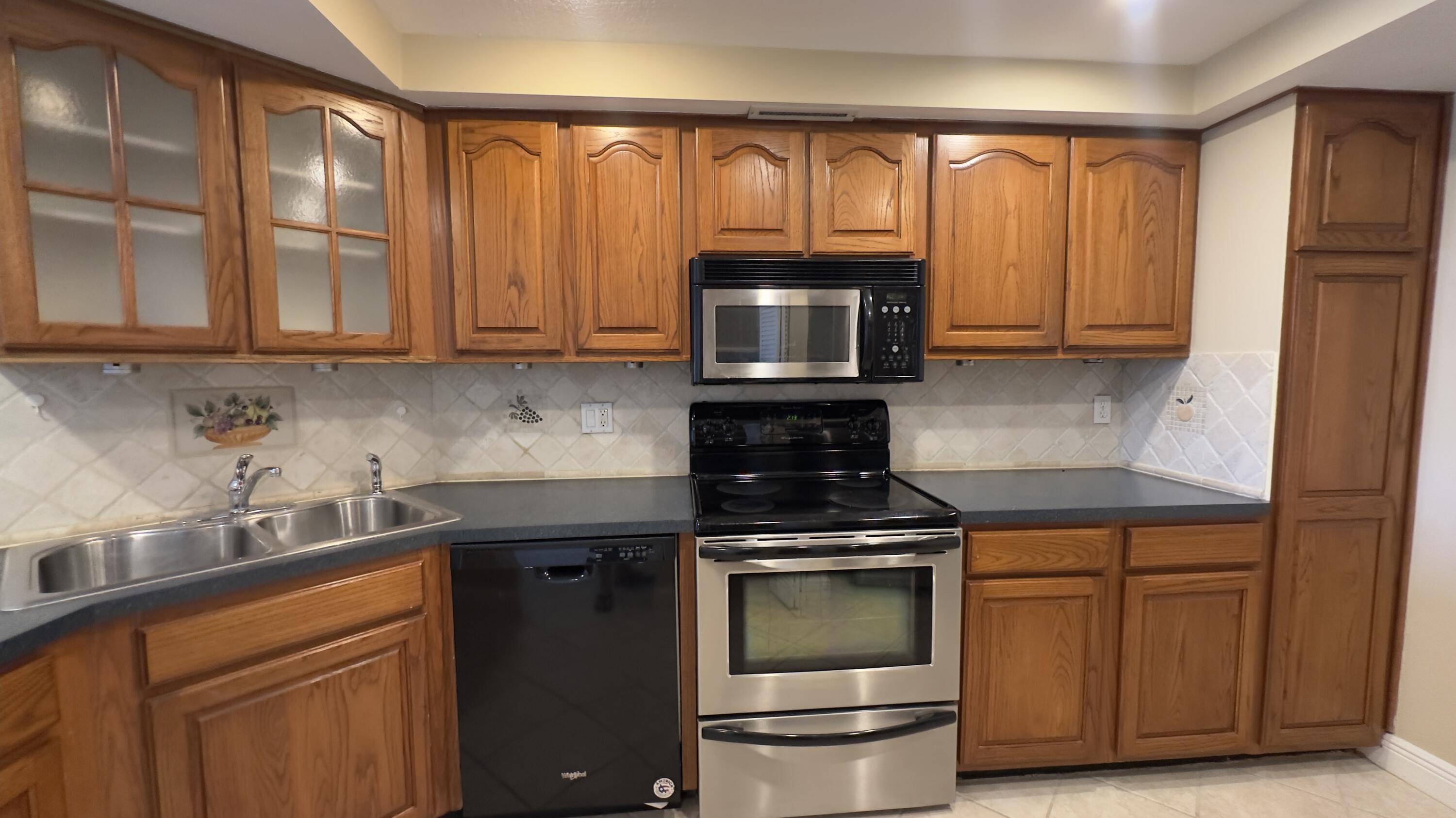 2425 Presidential Way, Unit 203 West Palm Beach, FL 33401 - Photo 3 of 35 a kitchen with granite countertop wooden cabinets and a stove top oven