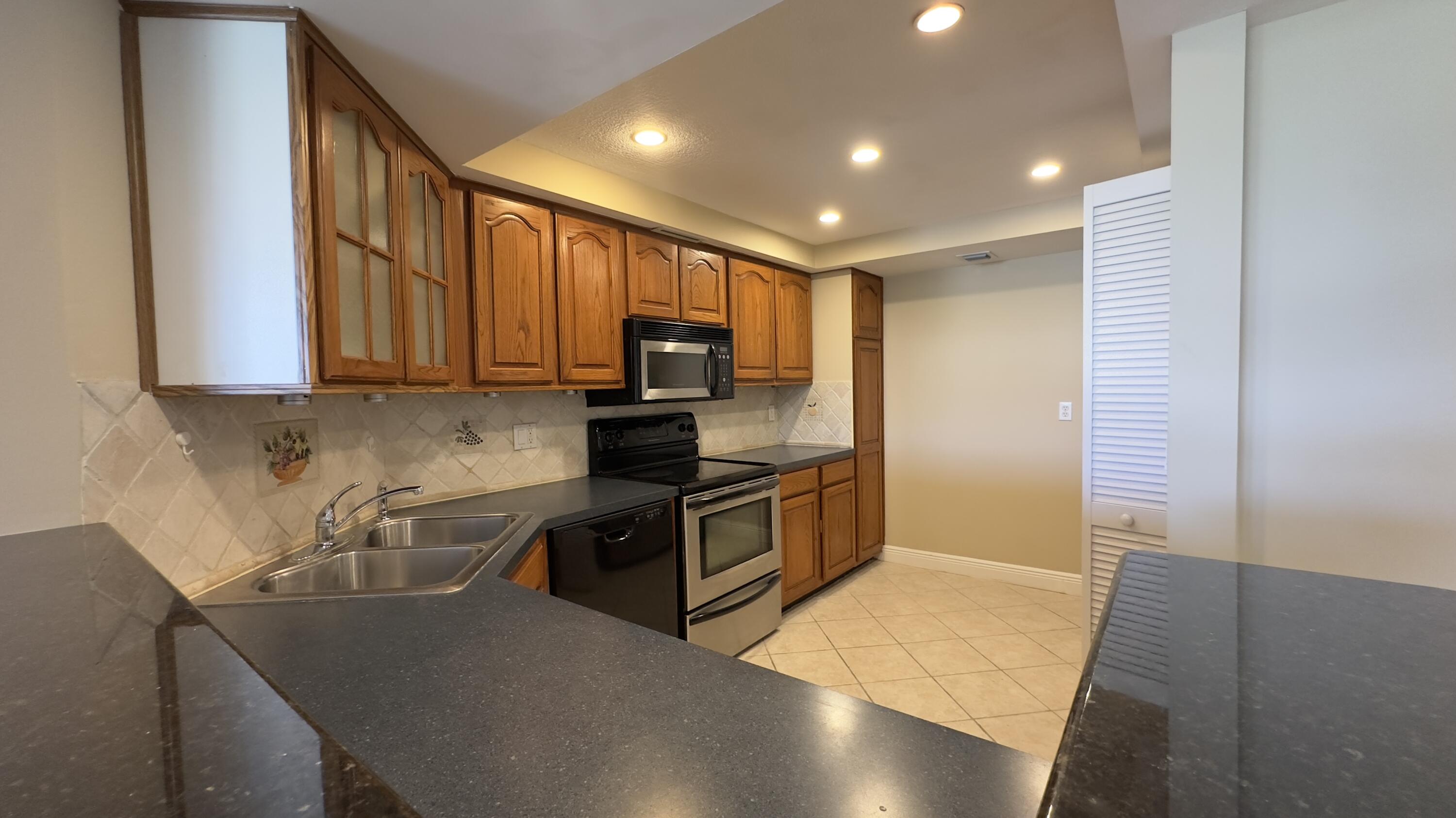 2425 Presidential Way, Unit 203 West Palm Beach, FL 33401 - Photo 5 of 35 a kitchen with stainless steel appliances granite countertop a sink stove and refrigerator