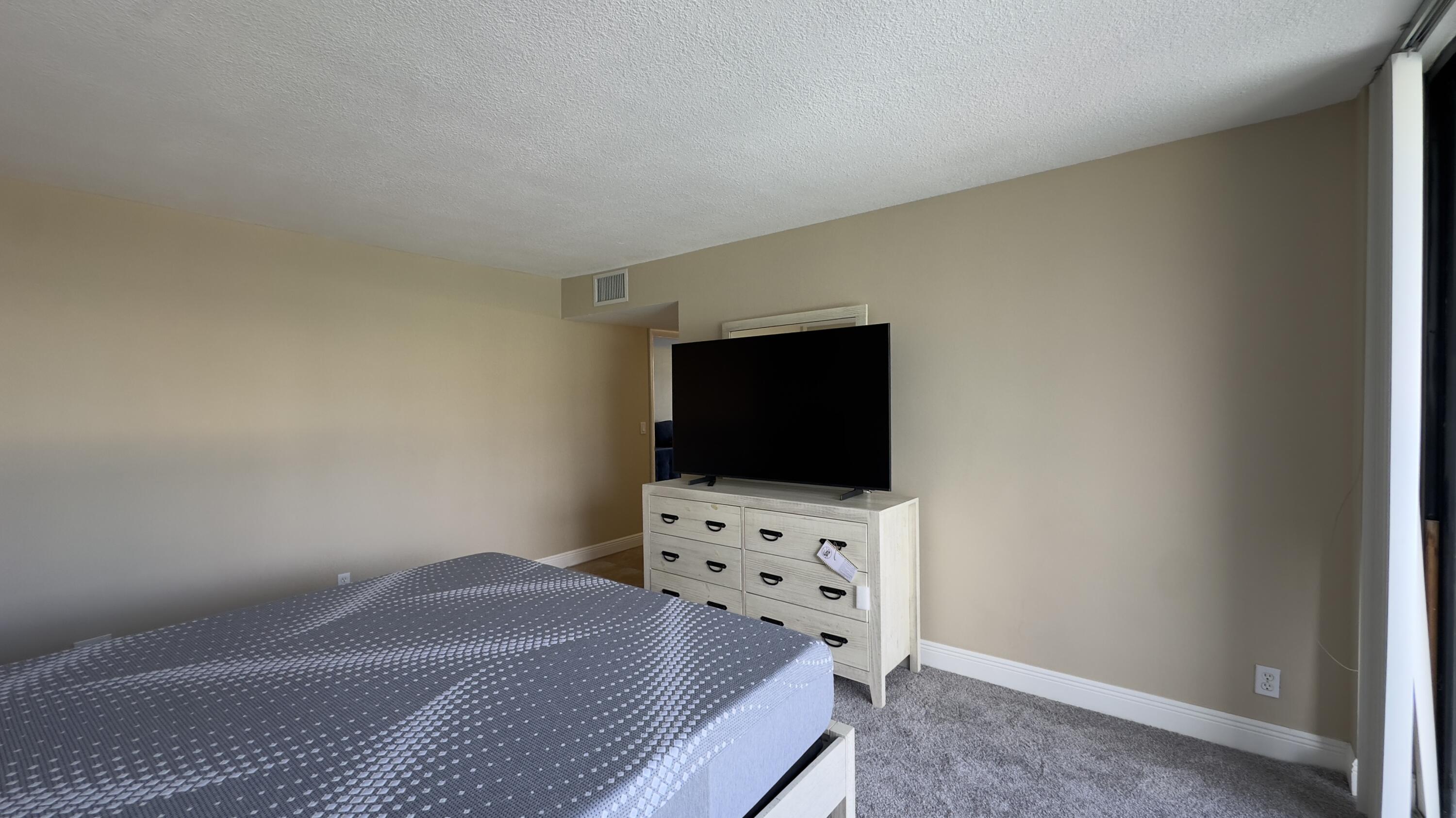 2425 Presidential Way, Unit 203 West Palm Beach, FL 33401 - Photo 10 of 35 a bedroom with a bed and a flat screen tv