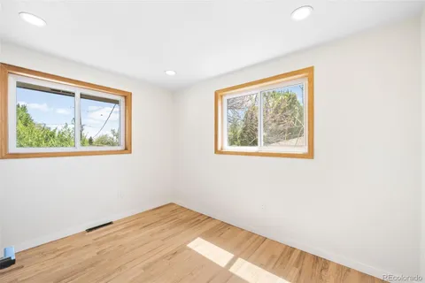 a view of an empty room with wooden floor and window