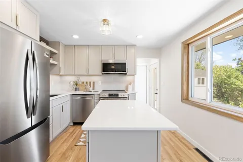 a kitchen with a refrigerator a stove top oven a sink and a window