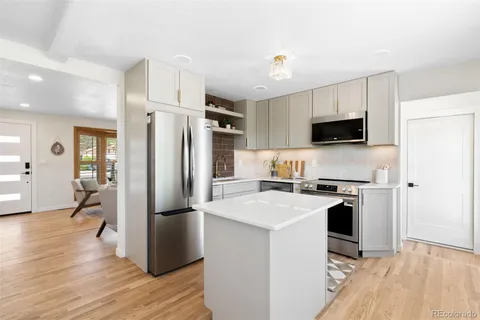 a kitchen with a refrigerator a stove top oven and wooden floor
