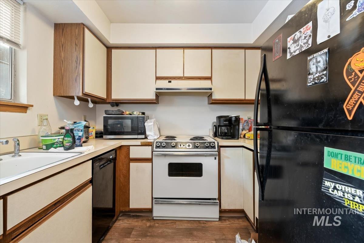 33 South Mike Street Boise, ID 83705 - Photo 25 of 50 Kitchen with black appliances, light countertops, dark wood-type flooring, under cabinet range hood, and brown cabinets