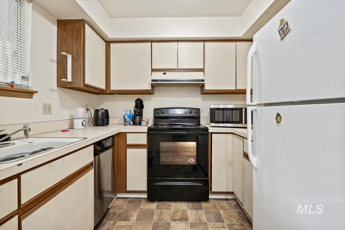 33 South Mike Street Boise, ID 83705 - Photo 48 of 50 Kitchen featuring appliances with stainless steel finishes, light countertops, stone finish flooring, and brown cabinetry