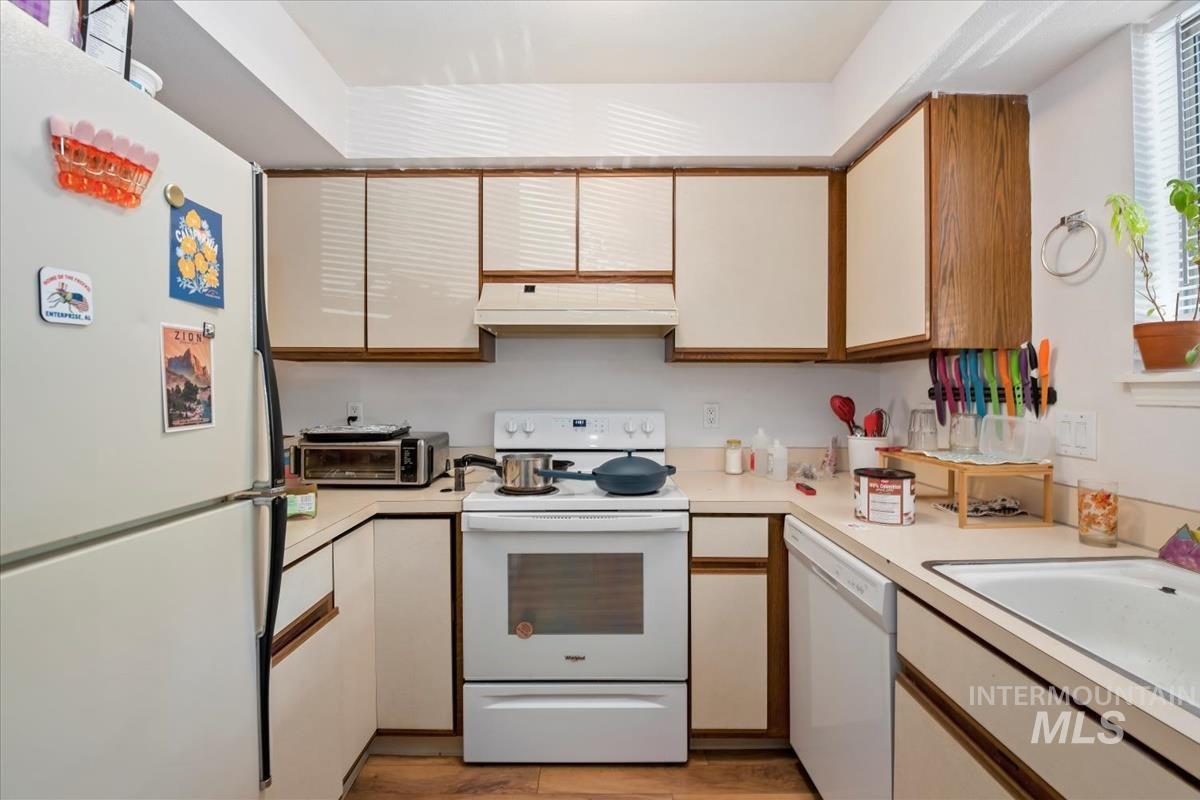 33 South Mike Street Boise, ID 83705 - Photo 9 of 50 Kitchen featuring white appliances, light countertops, brown cabinets, and white cabinetry