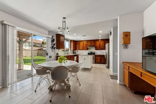 a open kitchen with stainless steel appliances granite countertop a stove top oven a sink dishwasher a dining table and chairs with wooden floor