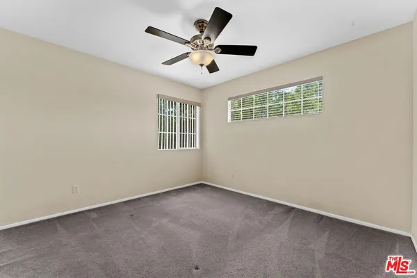 an empty room with ceiling fan and window