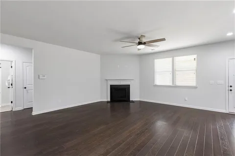 an empty room with wooden floor ceiling fan and windows