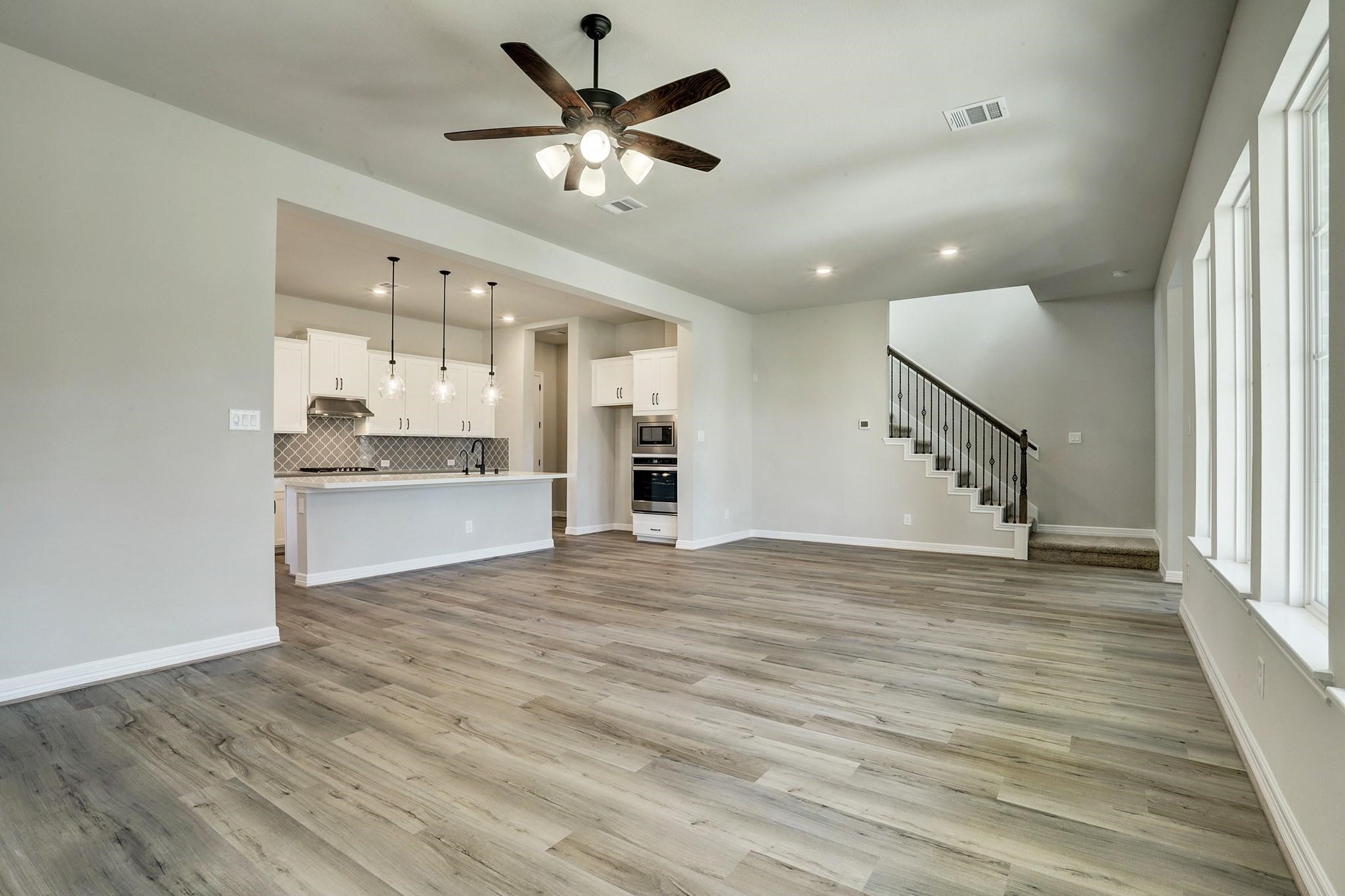 9522 Caddo Ridge Lane Cypress, TX 77433 - Photo 12 of 38 wooden floor in an empty room with a kitchen