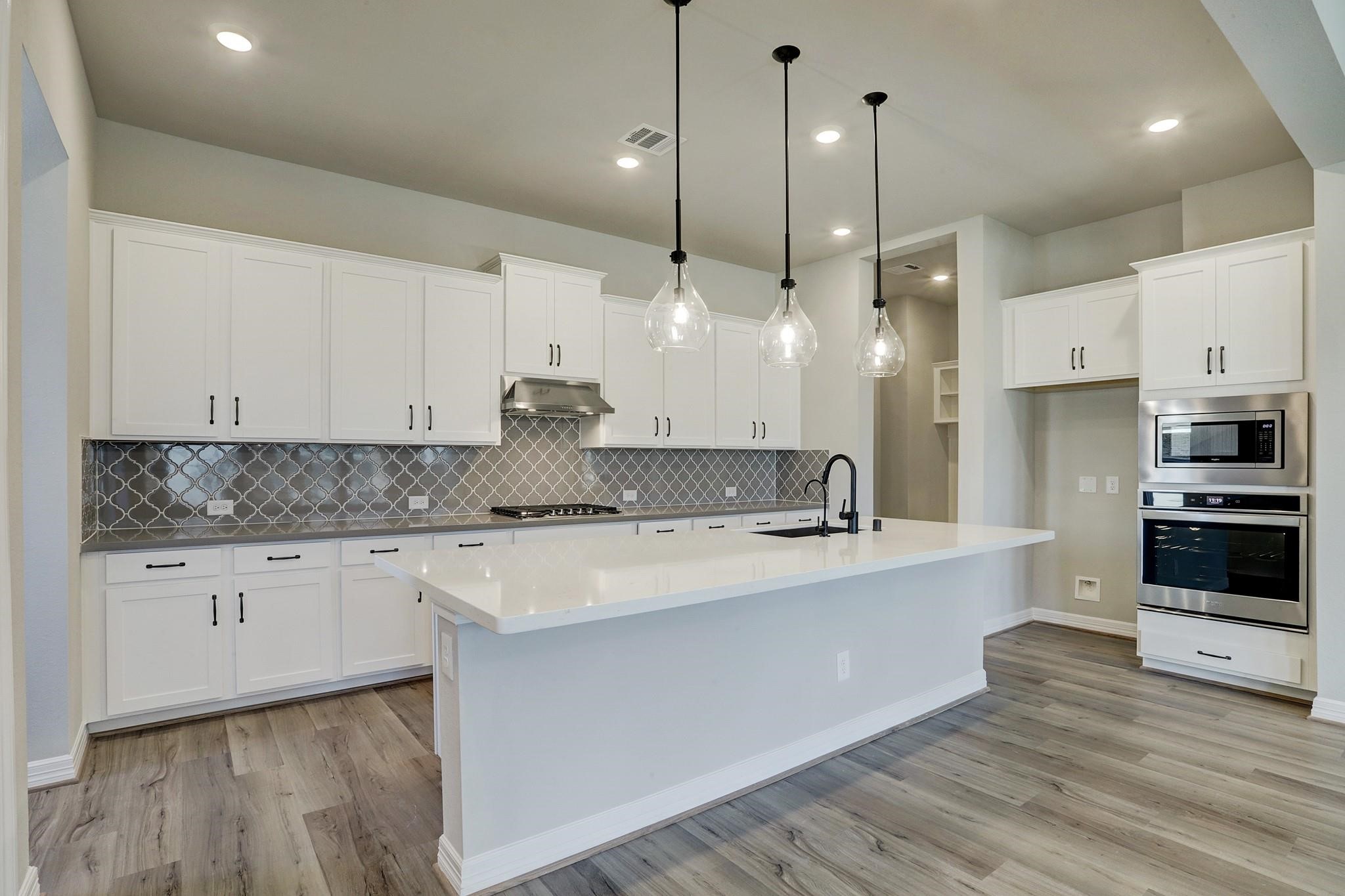 9522 Caddo Ridge Lane Cypress, TX 77433 - Photo 4 of 38 a view of a kitchen with kitchen island a sink stainless steel appliances and cabinets
