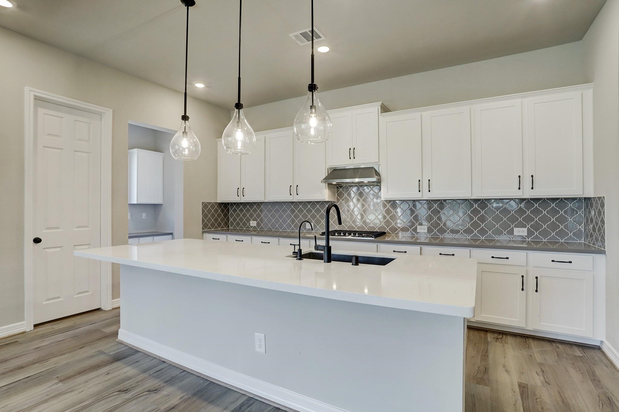 9522 Caddo Ridge Lane Cypress, TX 77433 - Photo 6 of 38 a kitchen with kitchen island a island a stove a sink and a wooden floor