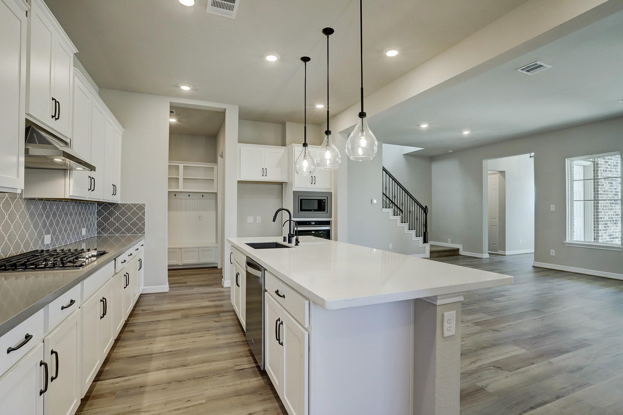 9522 Caddo Ridge Lane Cypress, TX 77433 - Photo 8 of 38 a large kitchen with kitchen island a stove a sink a center island and wooden floor