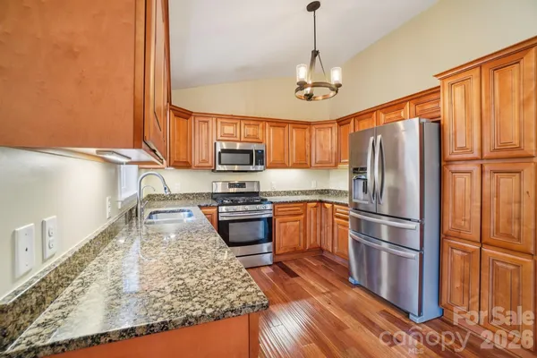 a kitchen with stainless steel appliances granite countertop a refrigerator a stove top oven a sink and dishwasher
