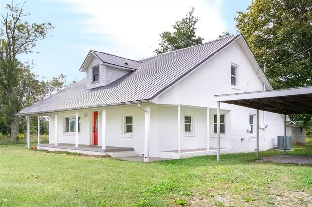 a view of a white house with a big yard and large trees